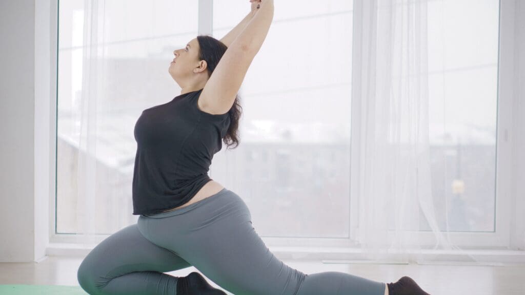 Person stretched out in a yoga pose in a brightly lit room.