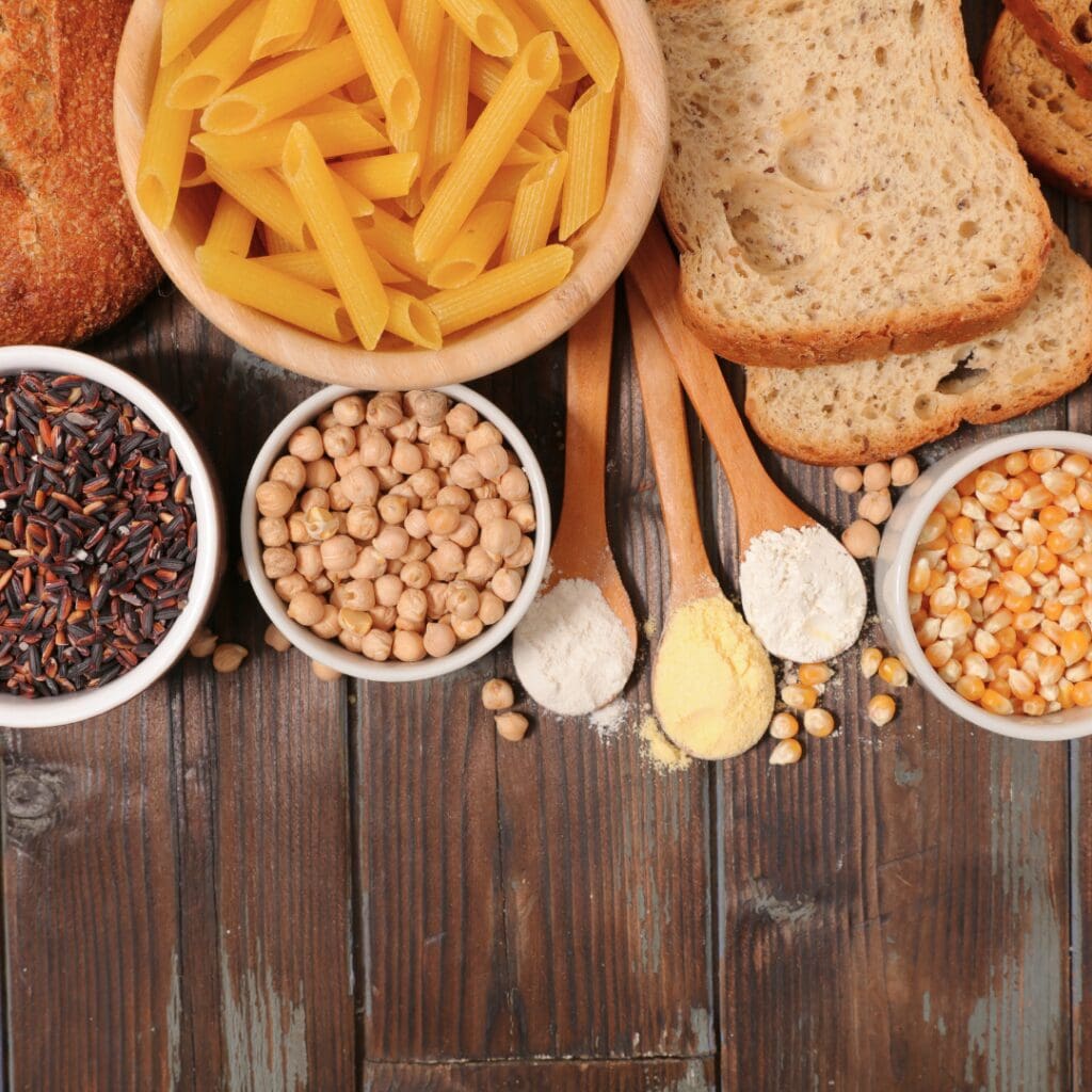 A flat-lay of different grains and pasta against a wood background.