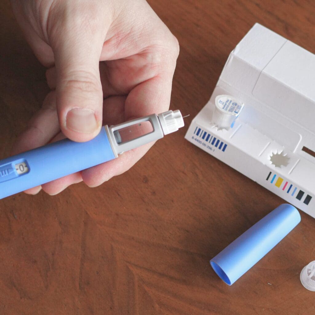 A hand holding a weight loss injection needle.