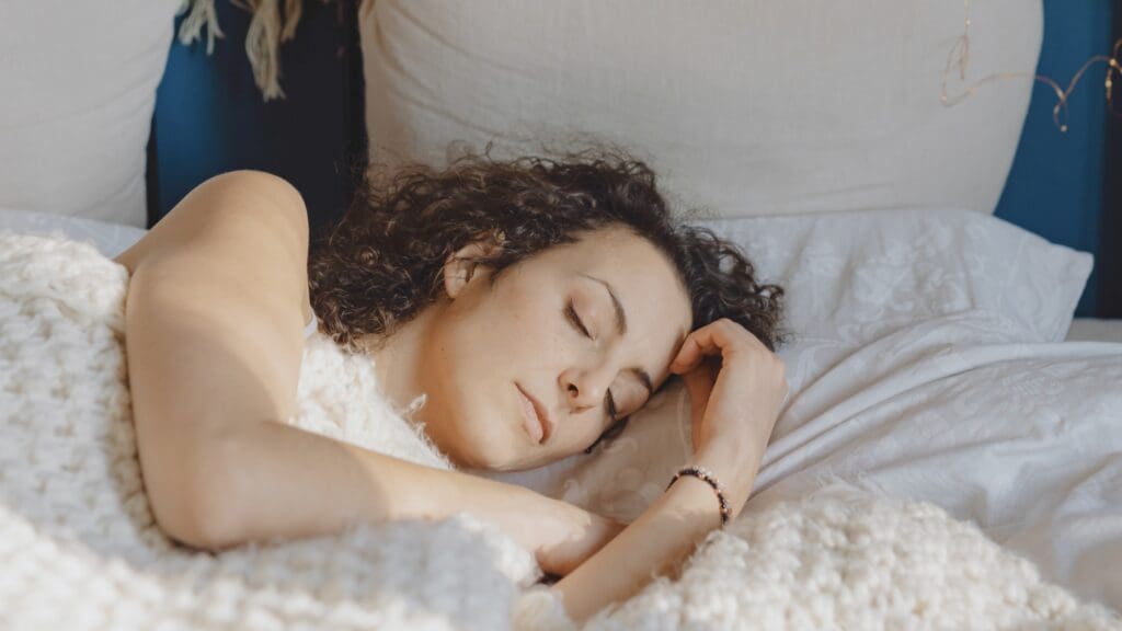 Person laying in a white bed and sleeping peacefully.