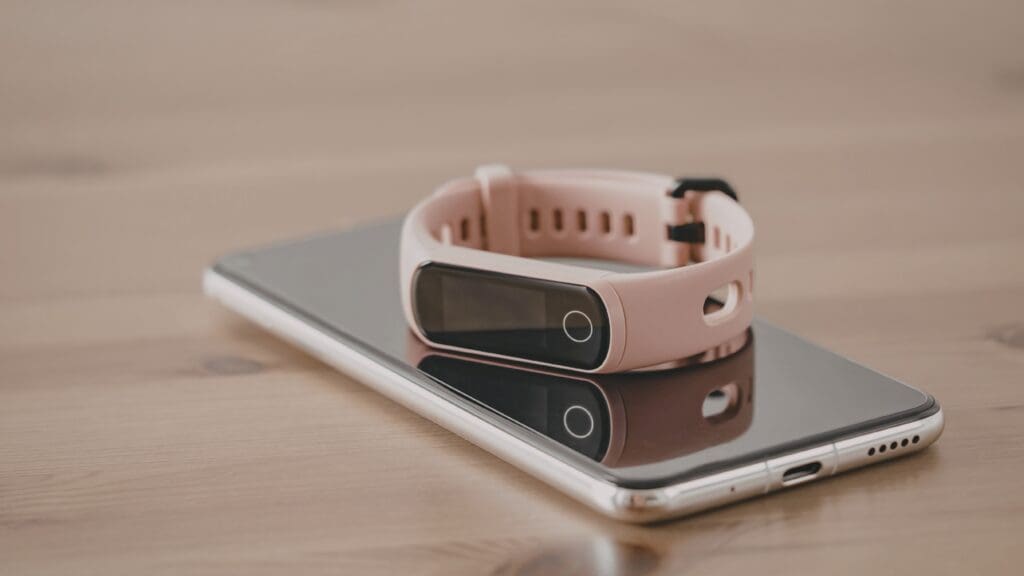 Fitness tracker and phone on a wooden table.